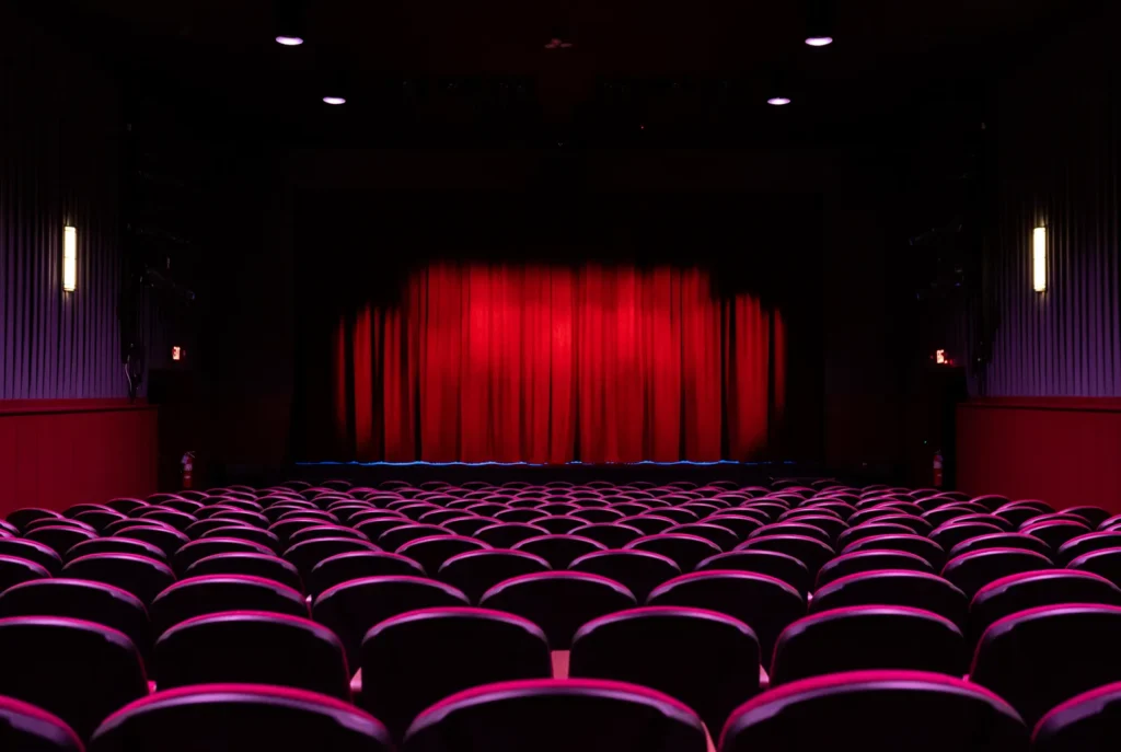 a theater with a red curtain and rows of chairs